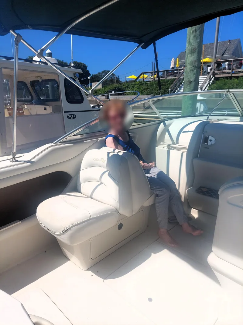 Slide: The Image of 2001 Sea Ray 225 Weekender boat interior with person seated, docked at marina. - 5