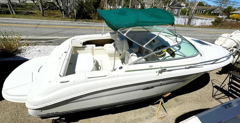 Slide: The Image of 2001 Sea Ray 225 Weekender boat with green canopy, parked on a trailer. - 8