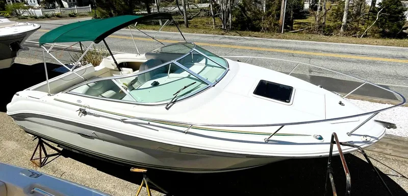 Slide: The Image of 2001 Sea Ray 225 Weekender boat with green canopy, parked on a trailer. - 9