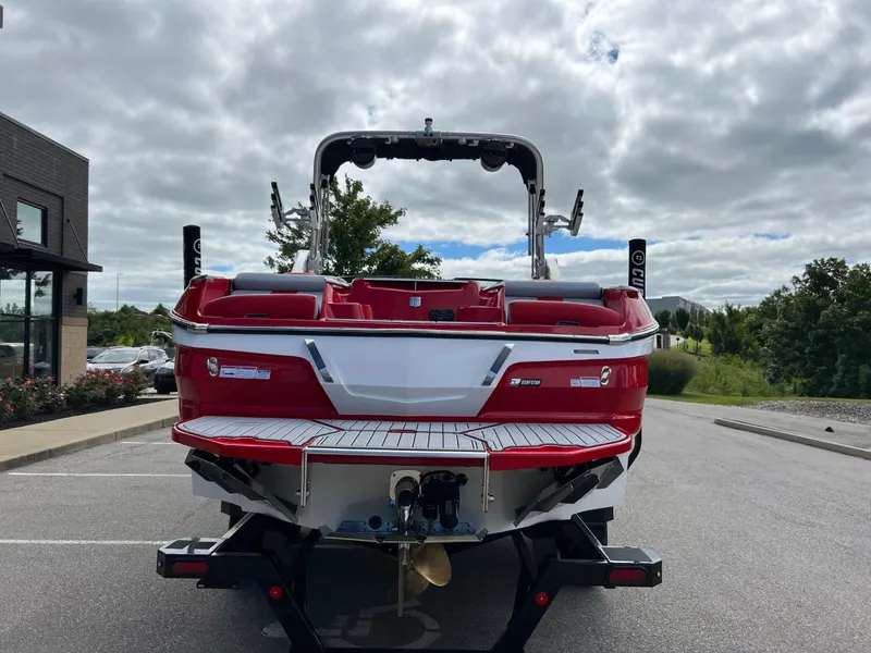 Slide: The Image of 2023 MasterCraft X24 boat, red and white, parked outdoors on a cloudy day. - 4
