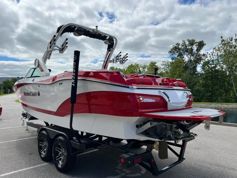 Slide: The Image of 2023 MasterCraft X24 boat on trailer, red and white design, parked outdoors. - 5