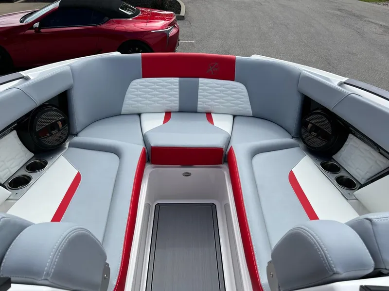 Slide: The Image of 2023 MasterCraft X24 boat interior with red and gray seating, cup holders, and speakers. - 8