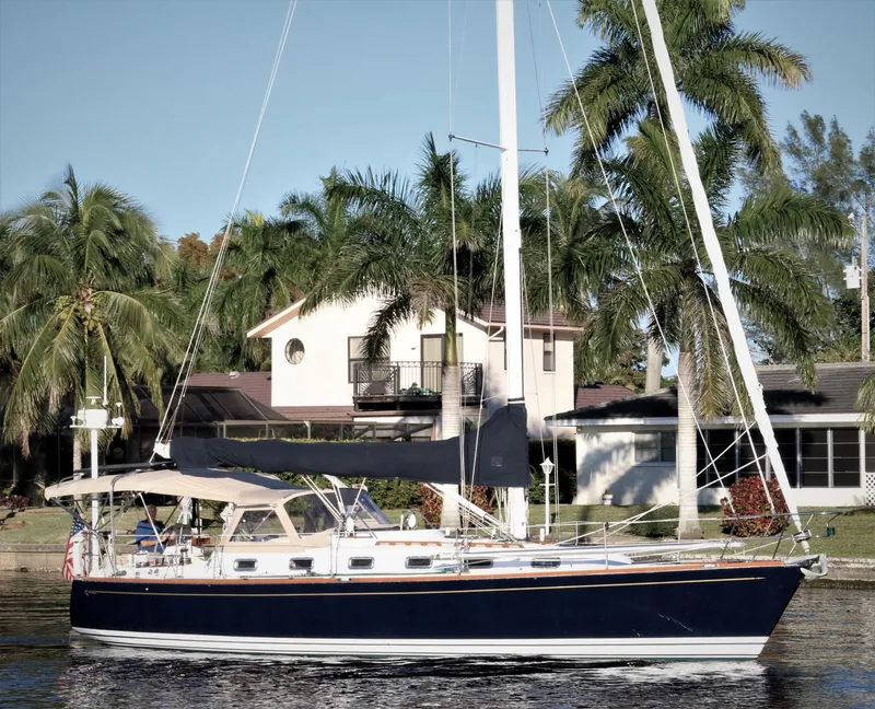 The Image of Sailboat Tartan 4100 (1998) docked near palm trees and waterfront homes. - 0