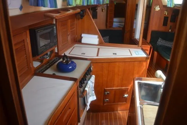 Slide: The Image of Interior of 1998 Tartan 4100 sailboat with wooden cabinetry and kitchen amenities. - 16