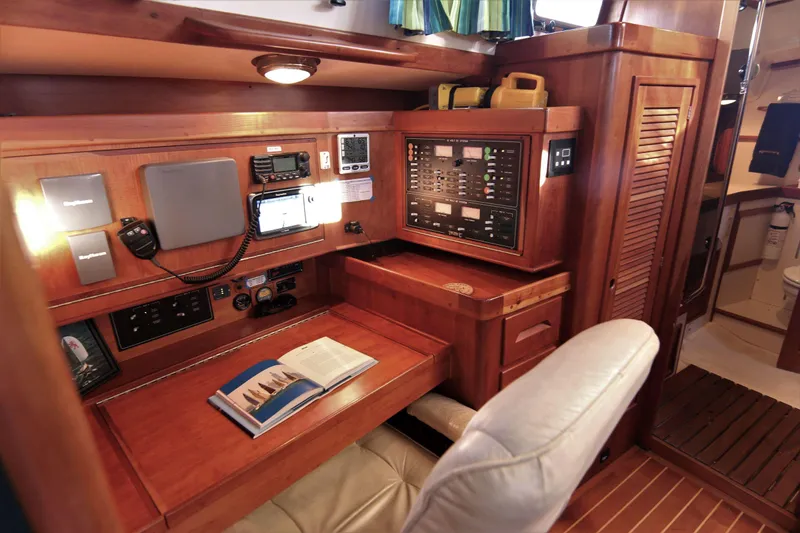 Slide: The Image of Navigation station inside 1998 Tartan 4100 sailboat with control panels and seating. - 38
