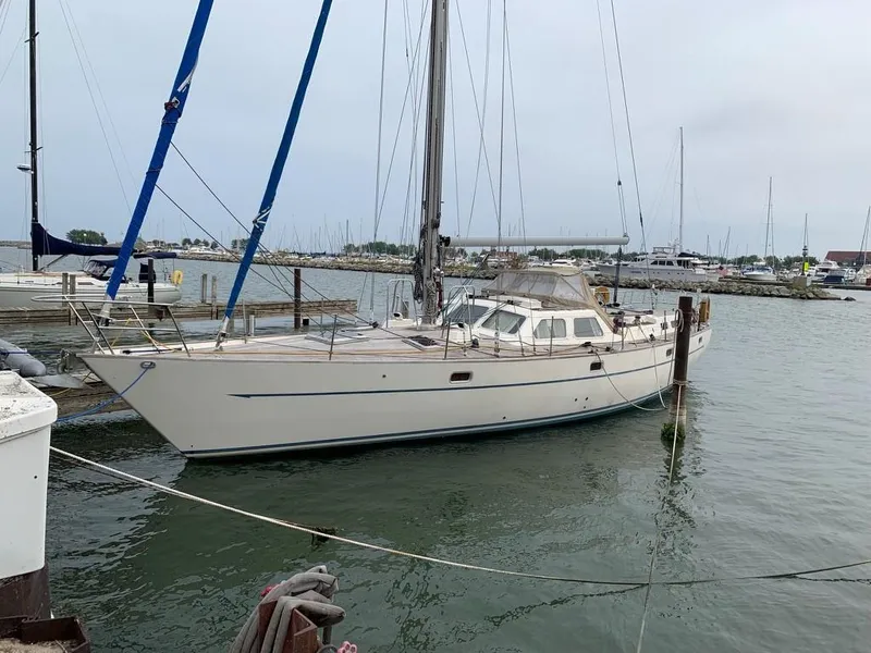 The Image of 1987 Oyster 46.5 sailboat docked in a marina, calm waters, overcast sky. - 0