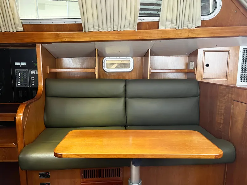 Slide: The Image of Interior of 1987 Oyster 46.5 yacht with green seating and wooden table. - 11