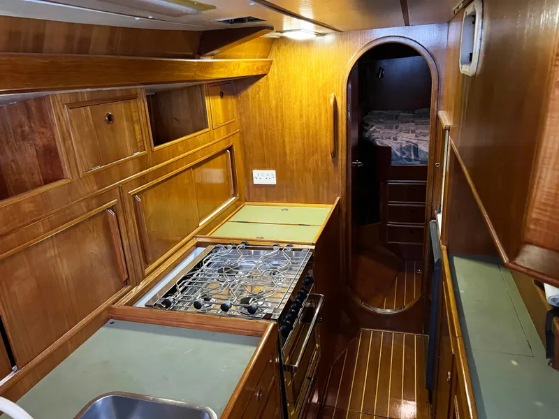Slide: The Image of Interior of 1987 Oyster 46.5 yacht with wooden cabinetry and compact kitchen. - 21