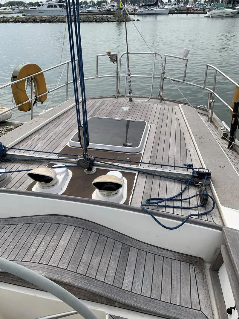 Slide: The Image of 1987 Oyster 46.5 sailboat deck with wooden finish, docked at marina. - 3
