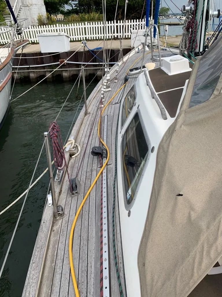 Slide: The Image of 1987 Oyster 46.5 sailboat docked, featuring teak deck and cabin details. - 4