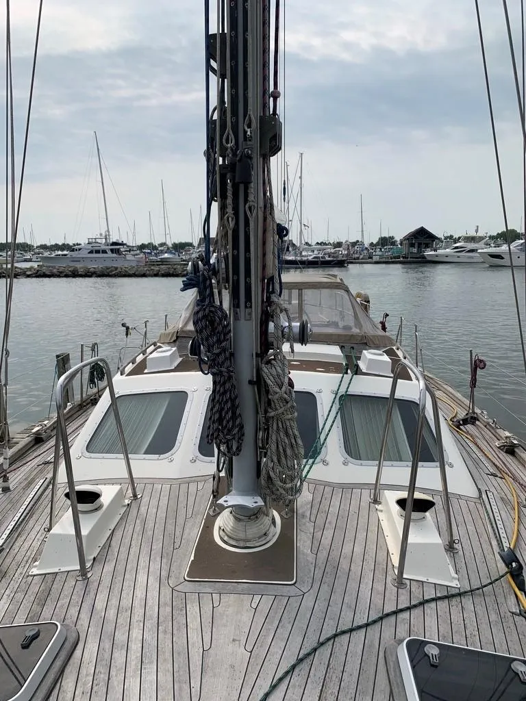 Slide: The Image of 1987 Oyster 46.5 sailboat deck with marina view, showcasing rigging and teak finish. - 5