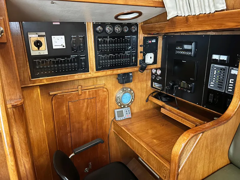 Slide: The Image of Navigation station of 1987 Oyster 46.5 yacht with control panels and wooden desk. - 8