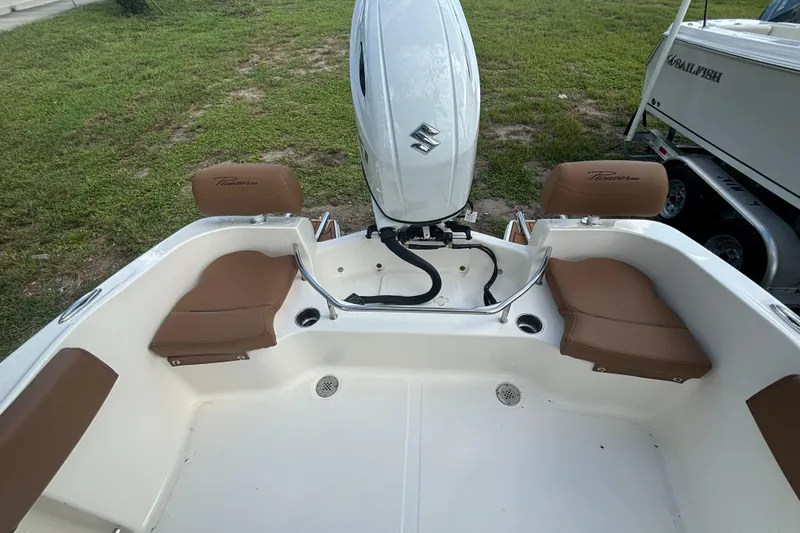 Slide: The Image of 2025 Pioneer 202 Sportfish boat interior with brown seating and Suzuki outboard motor. - 16
