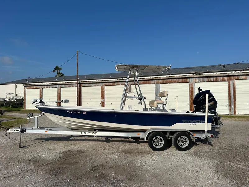 Slide: The Image of 2010 Pathfinder 2200-V boat on trailer, parked outdoors near storage units. - 1