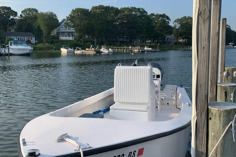 Slide: The Image of 2020 ROS Boats 20 Center Console docked by a serene waterfront with lush greenery. - 2