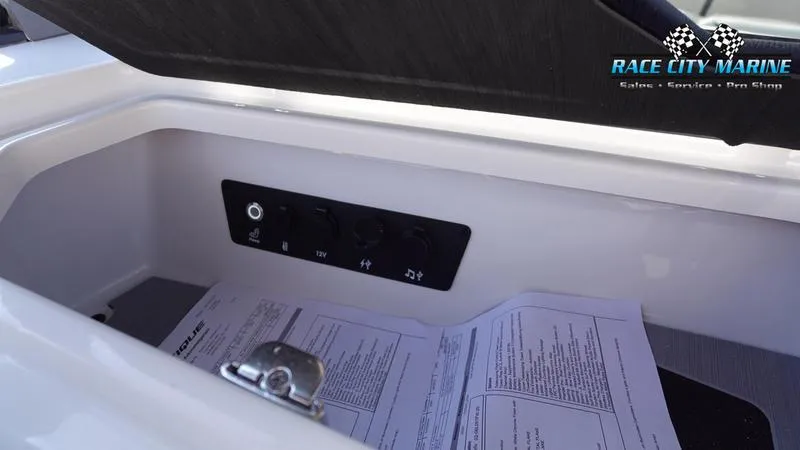 Slide: The Image of 2025 Nautique Super Air Nautique G23 storage compartment with control panel and documents. - 26