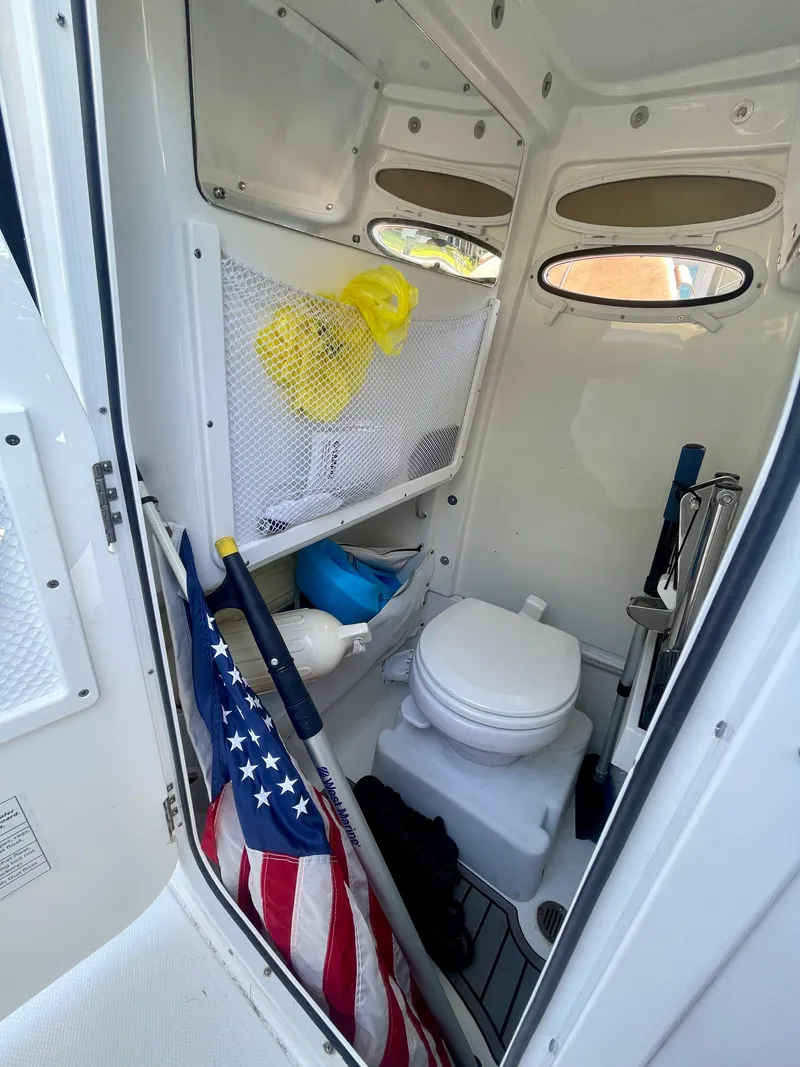 Slide: The Image of 2023 Sea Hunt Ultra 255 SE boat interior with toilet and storage area. - 11