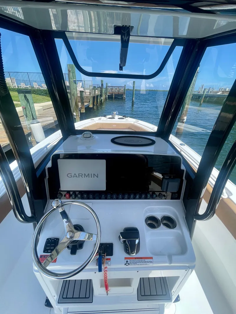 Slide: The Image of 2023 Sea Hunt Ultra 255 SE boat console with Garmin navigation, dockside view. - 2