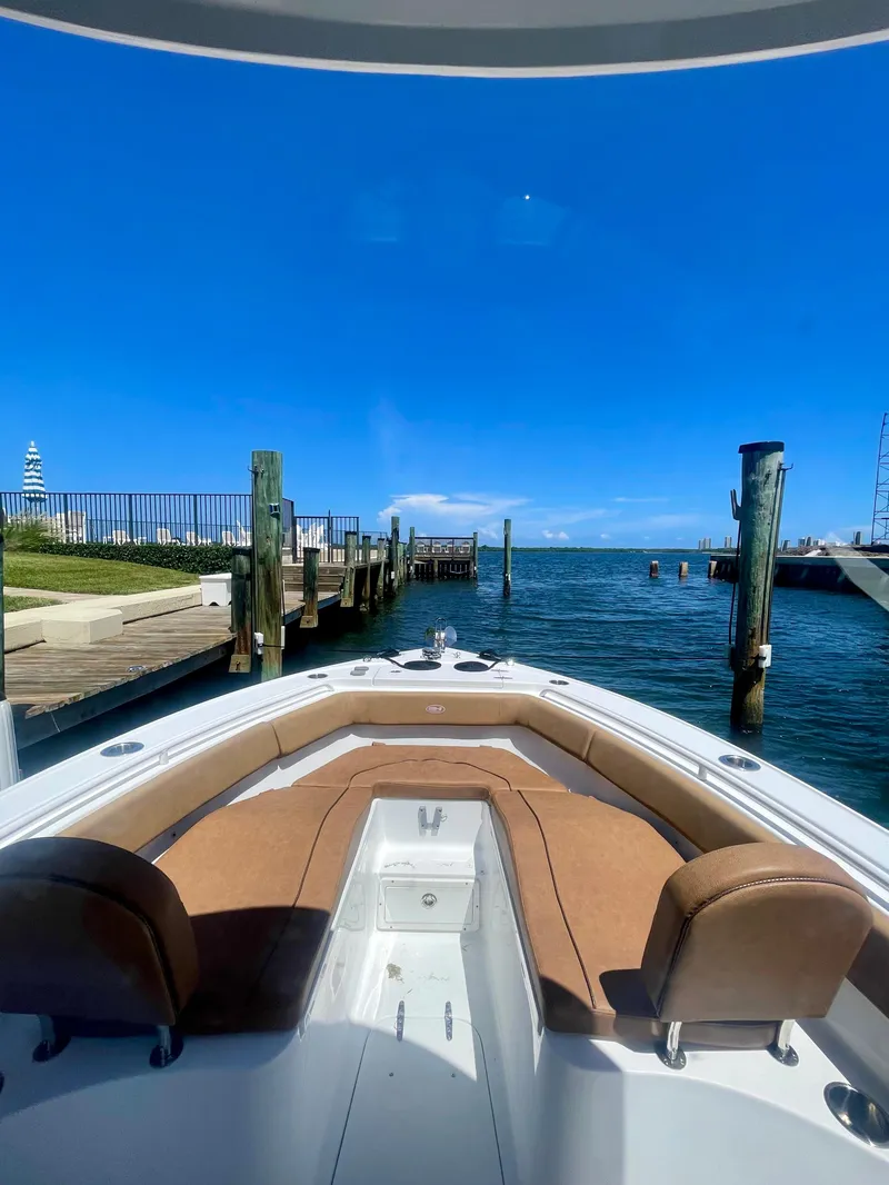 Slide: The Image of 2023 Sea Hunt Ultra 255 SE boat docked by a scenic waterfront. - 6
