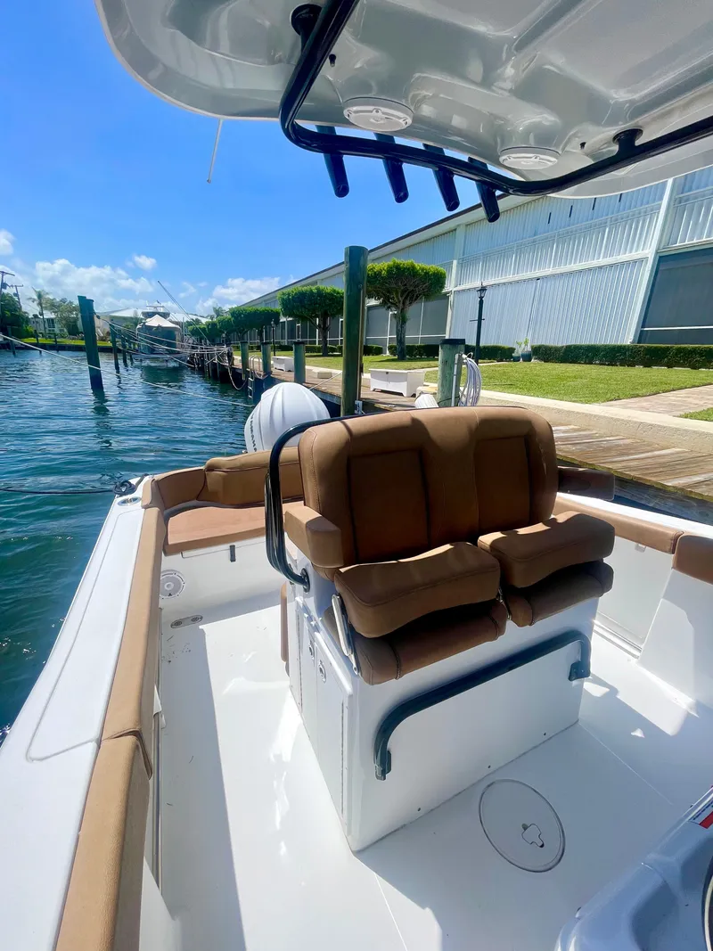 Slide: The Image of 2023 Sea Hunt Ultra 255 SE boat with tan seating, docked by waterfront homes. - 8