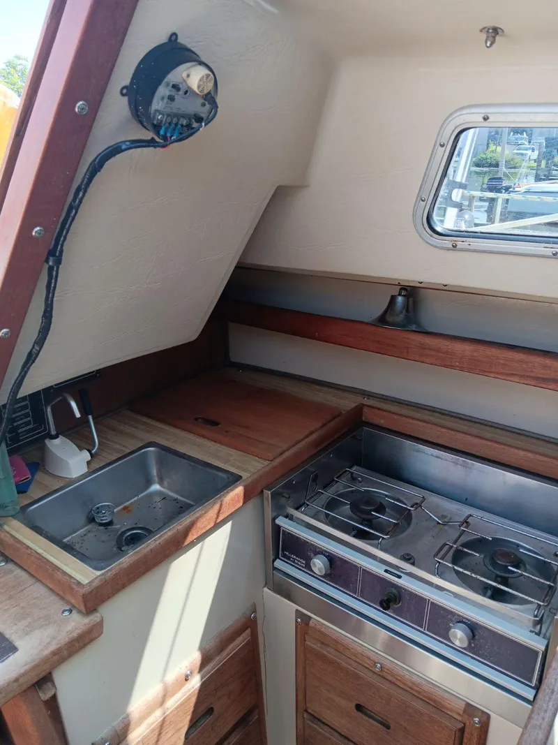 Slide: The Image of 1985 Catalina Fin Keel yacht interior with compact kitchen, stove, and sink. - 8
