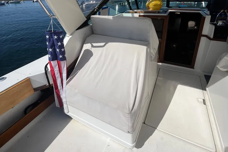 Slide: The Image of 1990 Tiara Yachts 3100 interior with covered seating and American flag. - 10