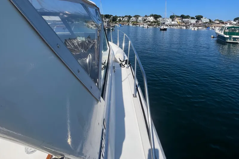 Slide: The Image of 1990 Tiara Yachts 3100 on calm water, docked in a scenic marina. - 11