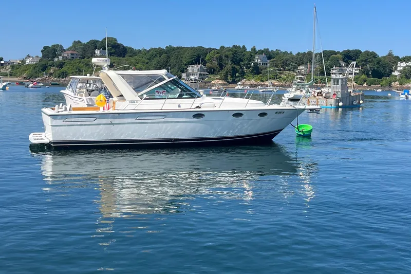 Slide: The Image of 1990 Tiara Yachts 3100 cruising on calm waters near a scenic shoreline. - 3