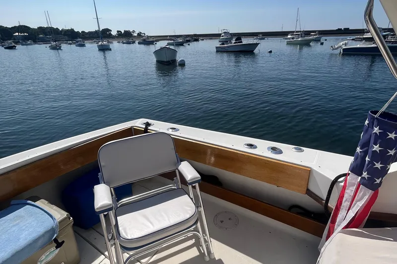 Slide: The Image of 1990 Tiara Yachts 3100 on calm water, featuring a deck chair and American flag. - 8