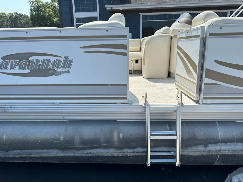 Slide: The Image of 2002 Crest Savannah pontoon boat with ladder and seating, docked near a building. - 2