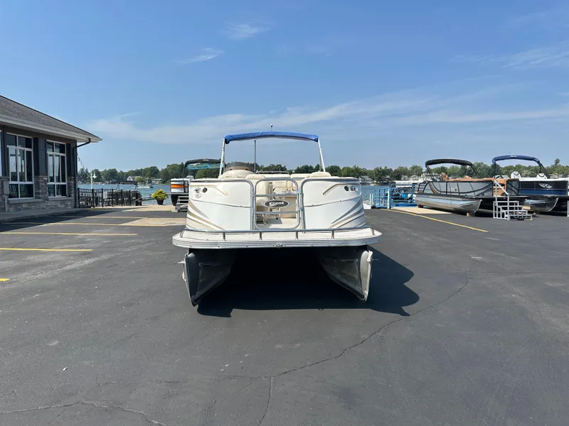 Slide: The Image of 2002 Crest Savannah pontoon boat parked on asphalt near a marina under a clear blue sky. - 3
