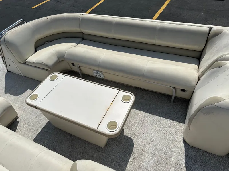 Slide: The Image of 2002 Crest Savannah boat interior with beige seating and table, featuring cup holders. - 6