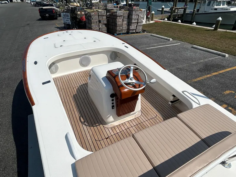 Slide: The Image of 2002 Bayshore Carolina Flats 20 boat with wooden deck and steering wheel, docked at marina. - 11