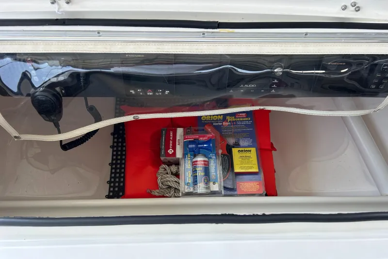 Slide: The Image of Boat storage compartment with safety gear, including flares and rope, in a 2002 Bayshore Carolina Flats 20. - 21