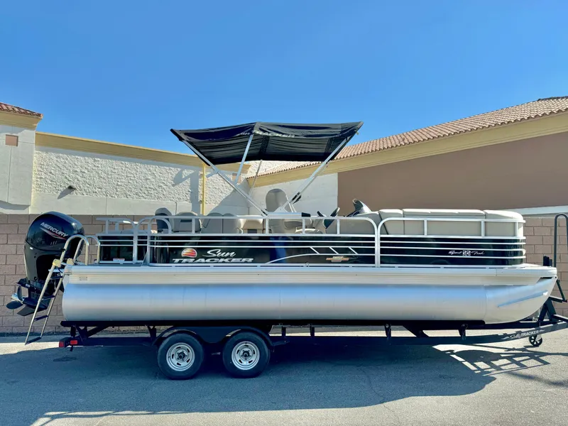 The Image of 2023 Sun Tracker Sport Fish 22 DLX pontoon boat on trailer, side view. - 1