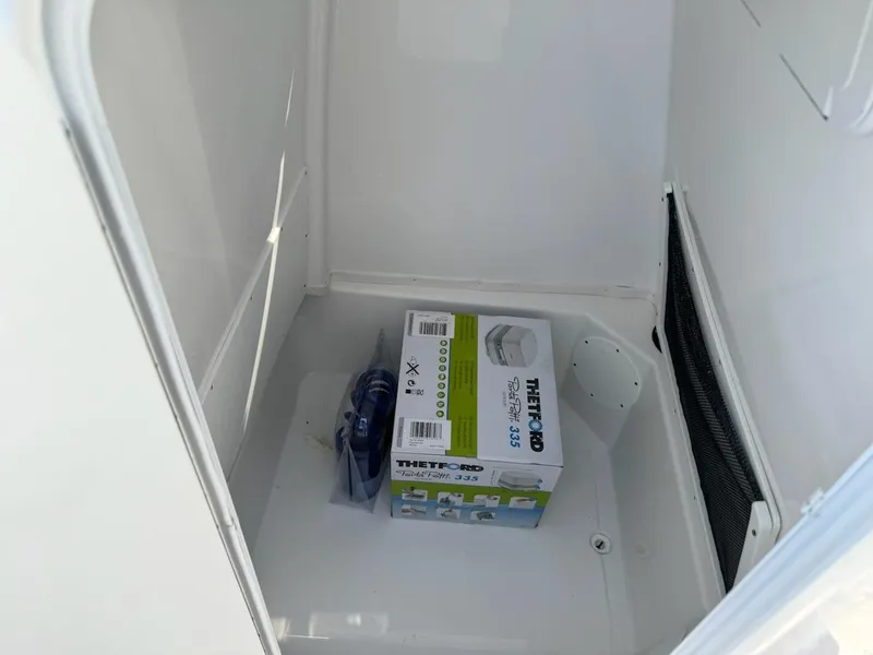Slide: The Image of 2025 NauticStar 242L Offshore storage compartment with a Thetford 365 box inside. - 13