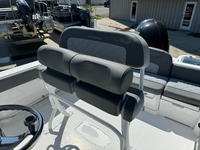 Slide: The Image of 2025 NauticStar 242L Offshore boat interior with cushioned seating and steering wheel. - 15