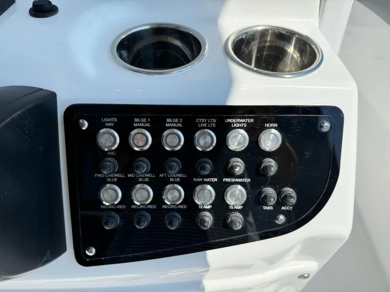 Slide: The Image of Control panel of 2025 NauticStar 242L Offshore boat with various switches and cup holders. - 19