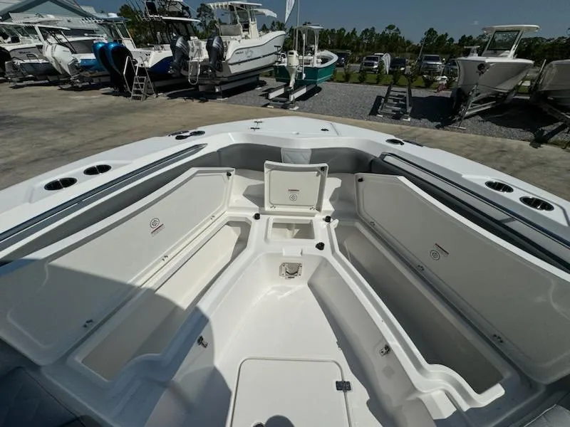 Slide: The Image of 2025 NauticStar 242L Offshore boat interior with open storage compartments, docked among other boats. - 20