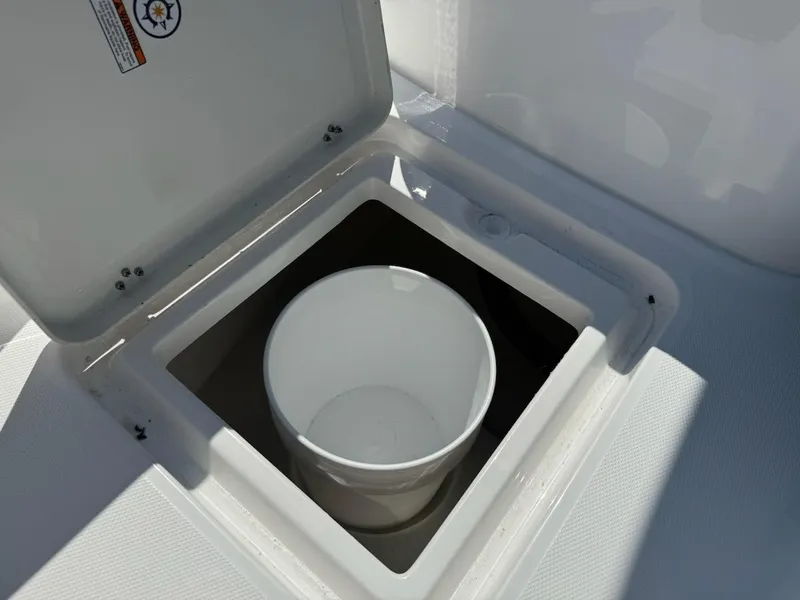 Slide: The Image of Open storage compartment on 2025 NauticStar 242L Offshore boat with white bucket inside. - 25