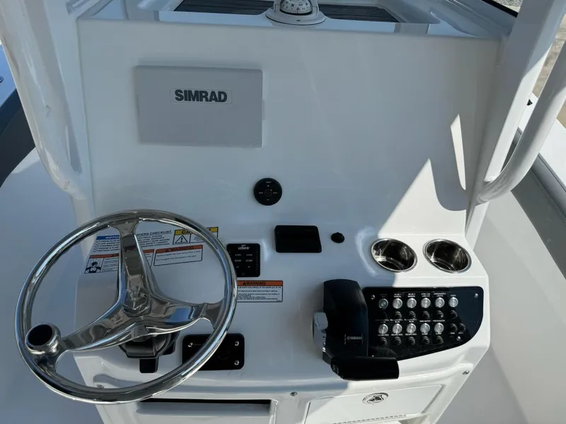 Slide: The Image of Control panel of 2025 NauticStar 242L Offshore boat with steering wheel and Simrad display. - 8