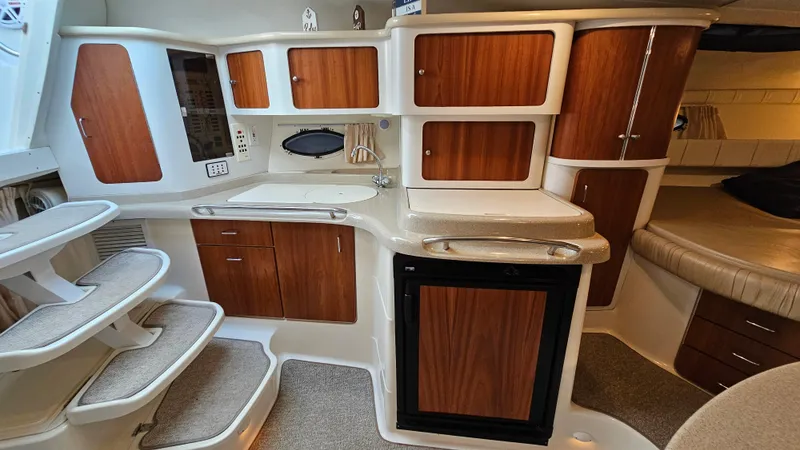 Slide: The Image of 2000 Chris-Craft 328 Express Cruiser interior with wooden cabinets and compact kitchen area. - 17