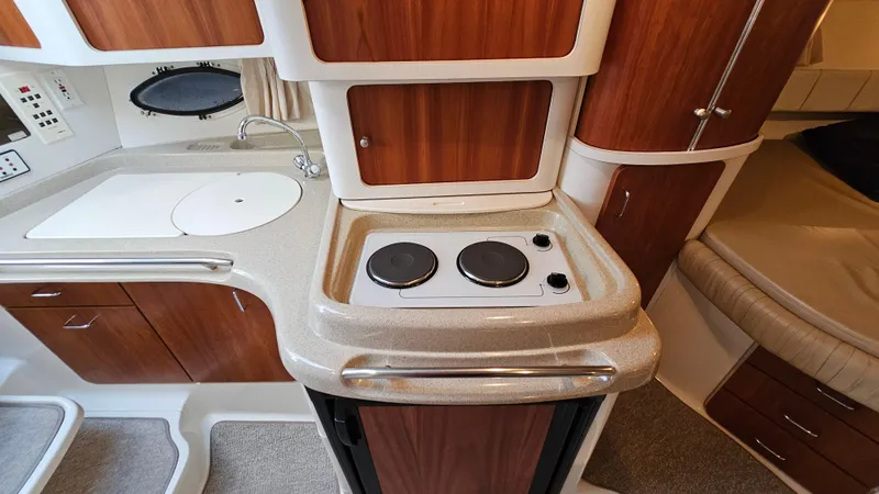 Slide: The Image of 2000 Chris-Craft 328 Express Cruiser interior with kitchenette, featuring stove and sink. - 24