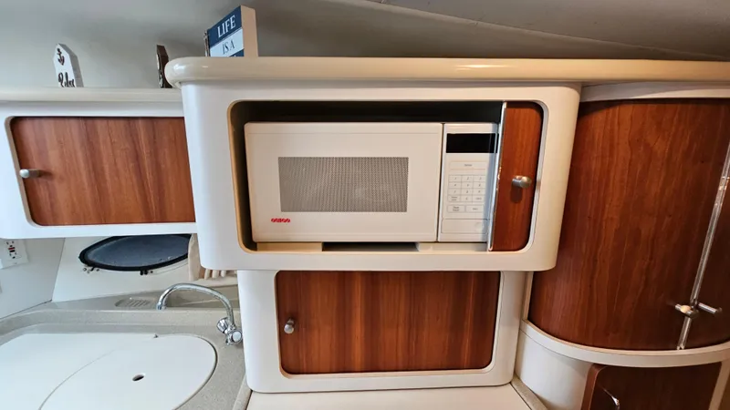 Slide: The Image of 2000 Chris-Craft 328 Express Cruiser kitchen with microwave and wooden cabinets. - 26