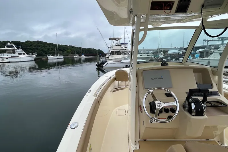 Slide: The Image of 2018 Scout 255 LXF boat docked in a marina, featuring a sleek helm and calm waters. - 16