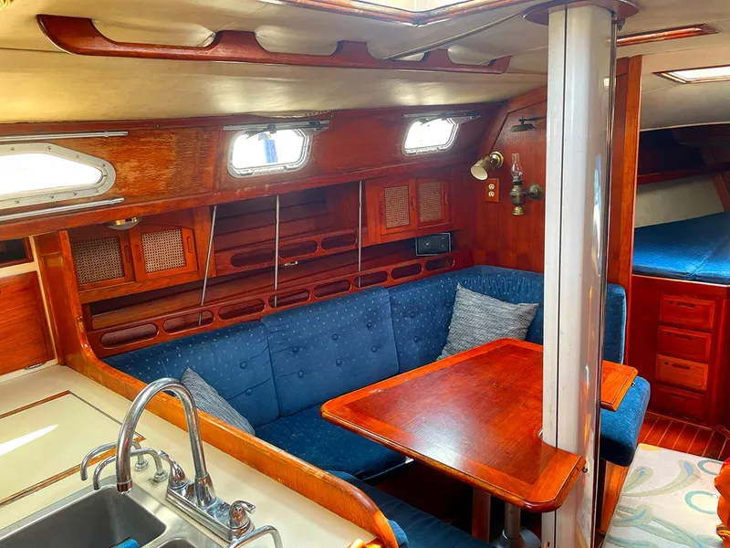 Slide: The Image of Interior of a 1990 Ericson 38-200 sailboat with wooden furnishings and blue seating. - 12