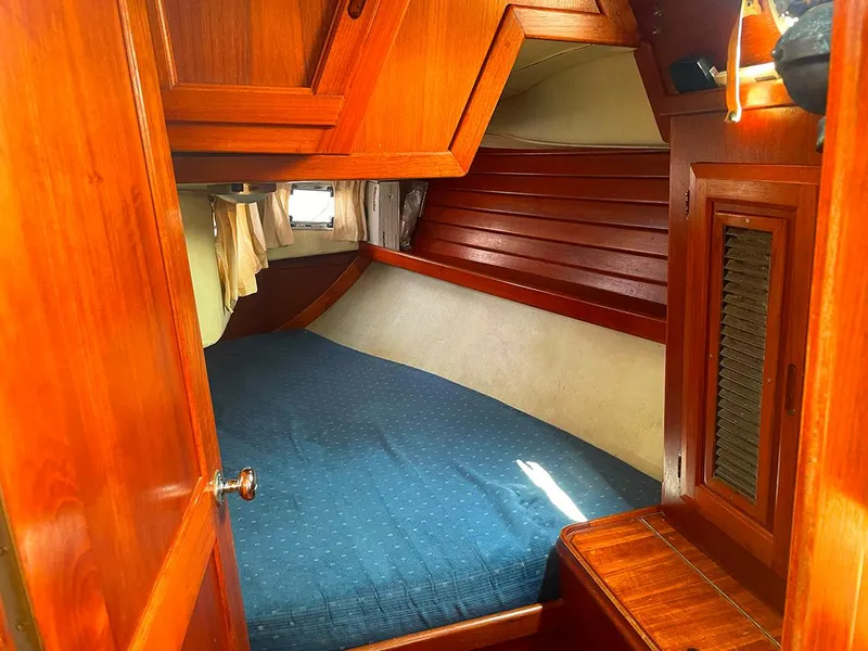 Slide: The Image of Cozy cabin interior of a 1990 Ericson 38-200 sailboat with wooden finishes and a blue bedspread. - 15