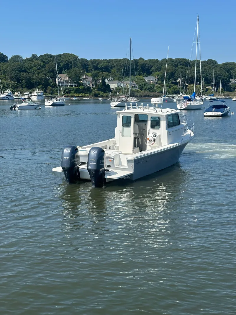 Slide: The Image of 2022 Parker 2520 XLD Sport Cabin boat on a calm lake with other boats. - 2