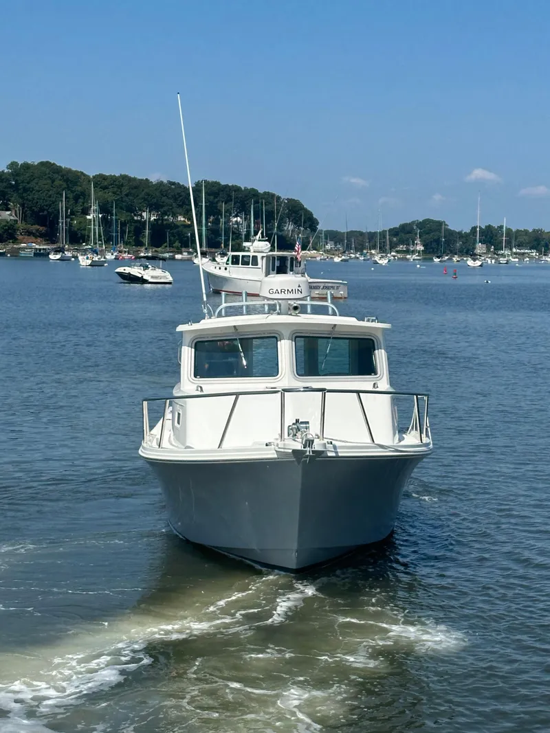 Slide: The Image of 2022 Parker 2520 XLD Sport Cabin boat on calm water, with marina background. - 3