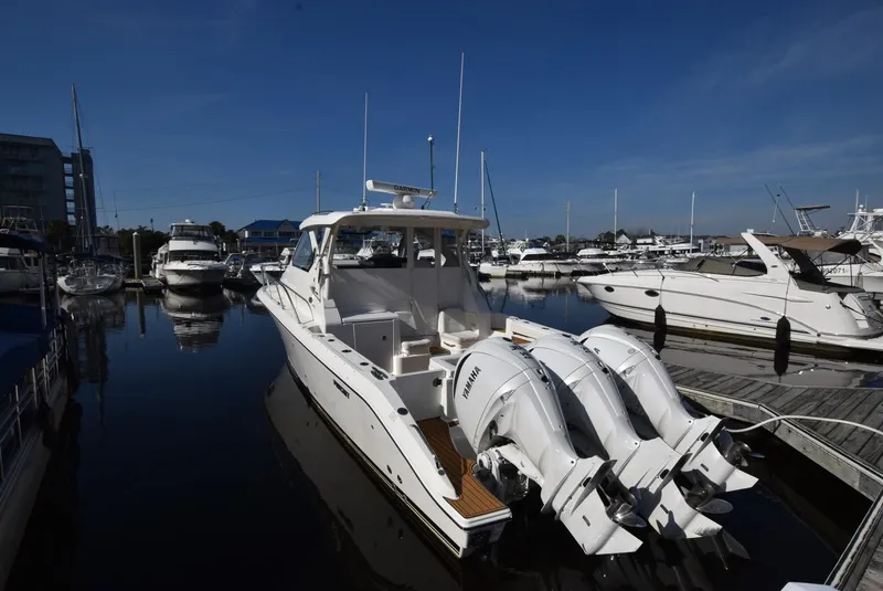 Slide: The Image of 2022 Pursuit OS 355 Offshore boat docked in a marina, featuring triple outboard engines. - 1